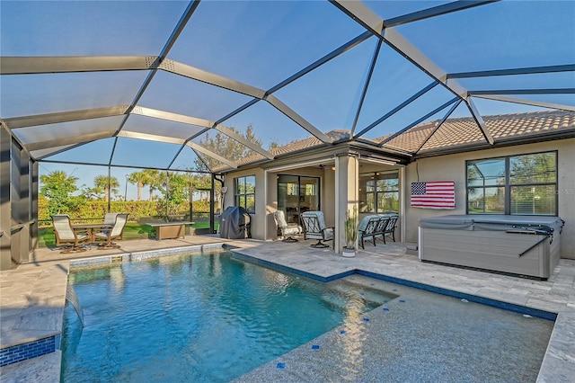 view of pool featuring glass enclosure, a patio area, and a hot tub