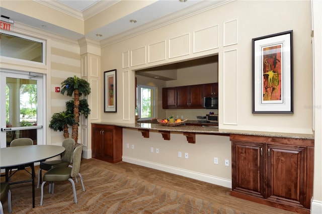 kitchen with plenty of natural light, crown molding, light stone counters, and dark wood-type flooring