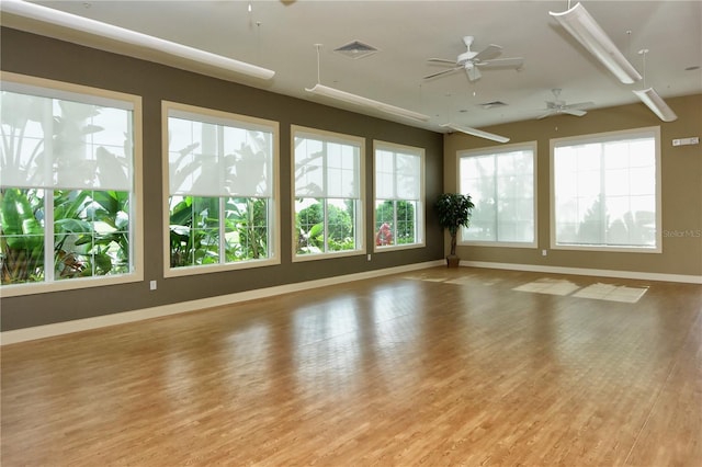 spare room with plenty of natural light, ceiling fan, and light wood-type flooring