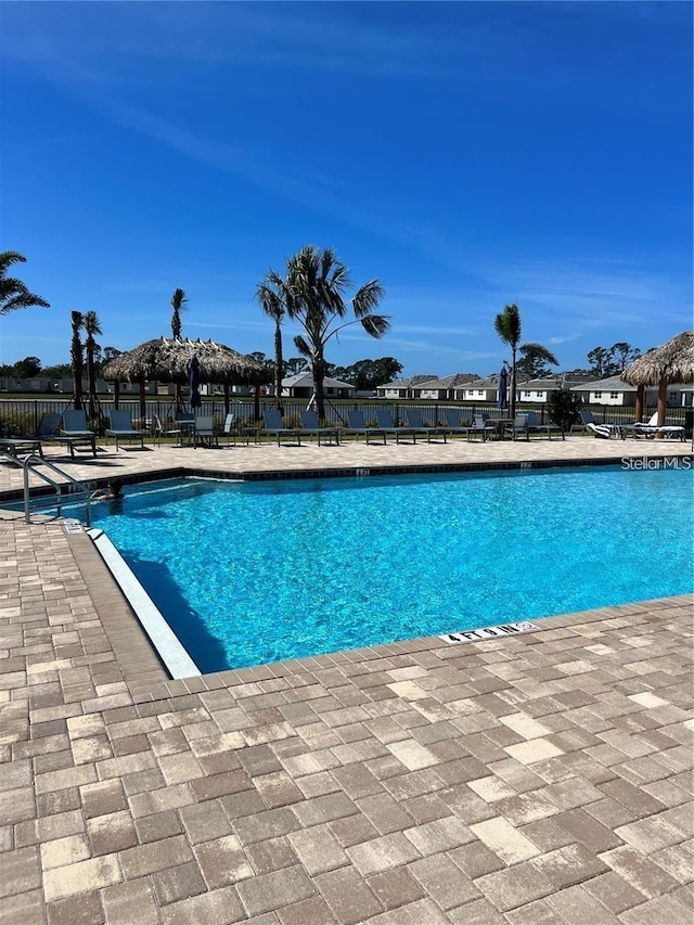 community pool with a patio area and fence