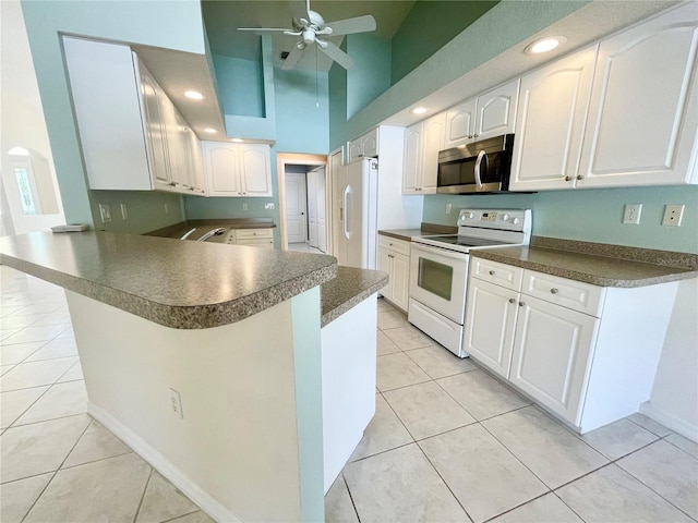 kitchen featuring white appliances, ceiling fan, a kitchen breakfast bar, white cabinets, and kitchen peninsula