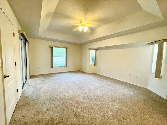 unfurnished bedroom with a raised ceiling, ceiling fan, light colored carpet, and a textured ceiling