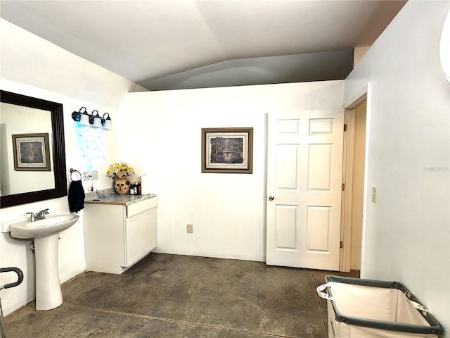 bathroom featuring concrete floors, lofted ceiling, and sink