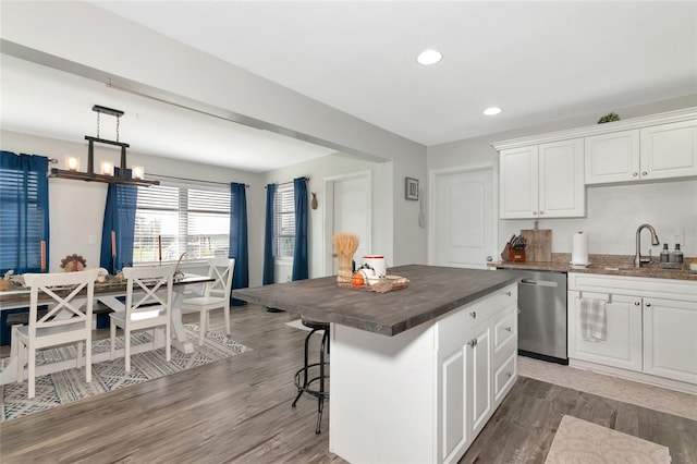 kitchen featuring a kitchen island, stainless steel dishwasher, sink, and white cabinets