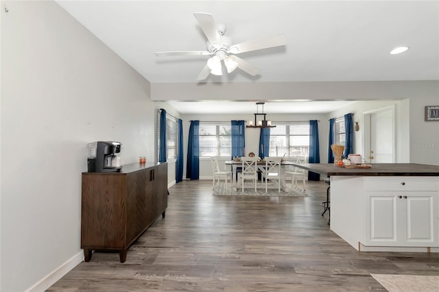 kitchen with dark wood-type flooring, a kitchen breakfast bar, white cabinetry, and decorative light fixtures