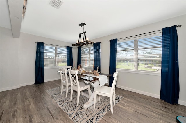 dining area featuring dark hardwood / wood-style flooring, a wealth of natural light, and a chandelier