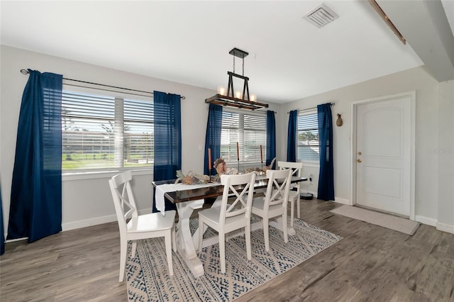 dining space with hardwood / wood-style flooring, a healthy amount of sunlight, and an inviting chandelier