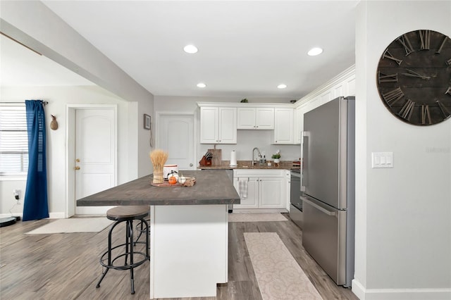 kitchen with a kitchen island, appliances with stainless steel finishes, light hardwood / wood-style floors, and white cabinets