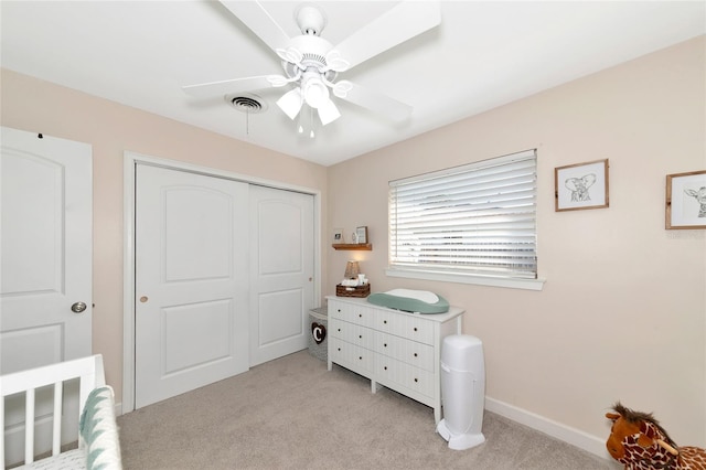 bedroom featuring ceiling fan, light carpet, and a closet