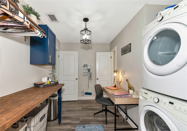 clothes washing area with stacked washing maching and dryer, an inviting chandelier, and dark hardwood / wood-style flooring