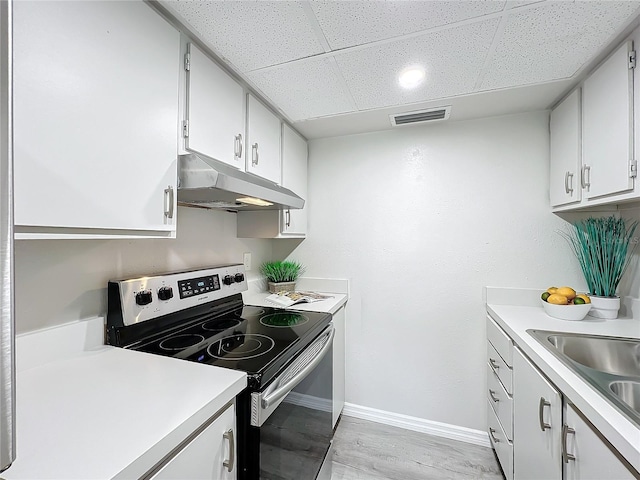 kitchen featuring light wood-type flooring, a drop ceiling, sink, white cabinetry, and stainless steel range with electric cooktop