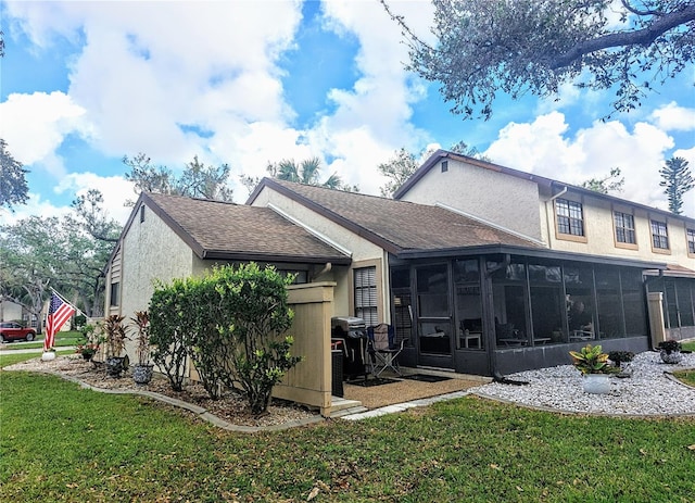 rear view of house featuring a lawn and a sunroom