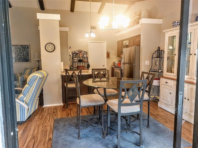 dining room featuring beam ceiling, hardwood / wood-style floors, and an inviting chandelier