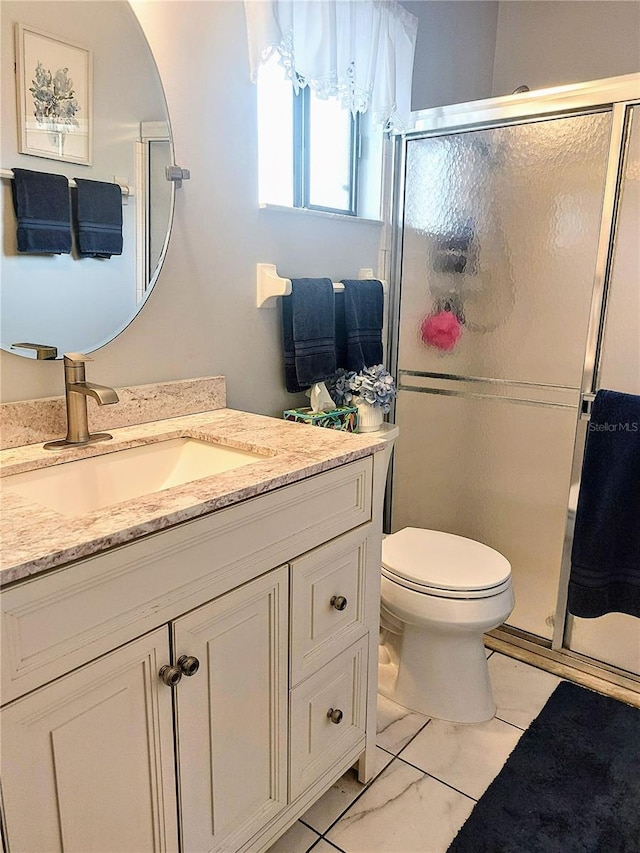 bathroom with vanity, toilet, and a shower with door