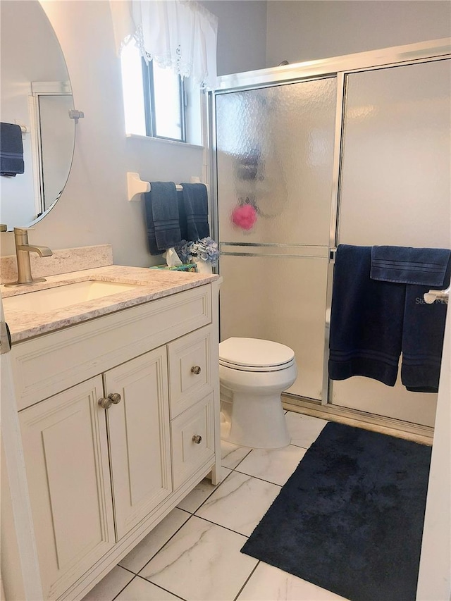 bathroom featuring vanity, toilet, and a shower with door