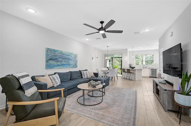 living room with light hardwood / wood-style floors, ceiling fan, and sink