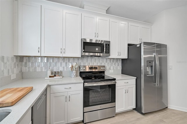 4008 Via Sienna Cir, Sarasota, FL 34243 - kitchen featuring stainless steel appliances, decorative backsplash, white cabinets, baseboards, and light stone counters