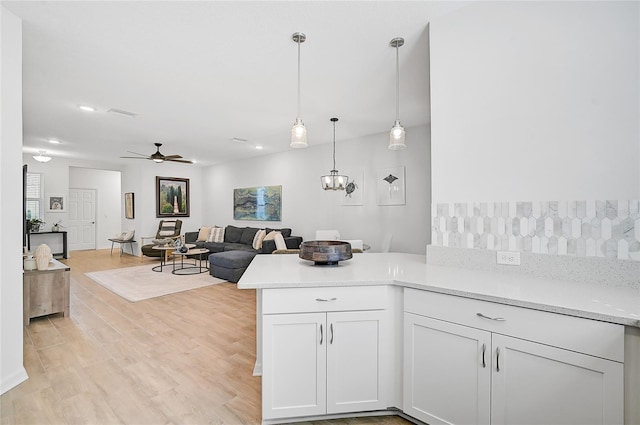 kitchen featuring white cabinetry, kitchen peninsula, ceiling fan, hanging light fixtures, and light hardwood / wood-style flooring