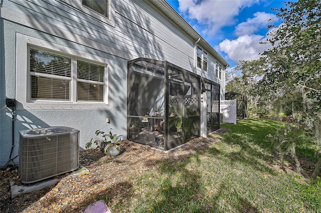 view of side of property featuring central air condition unit, a sunroom, and a yard