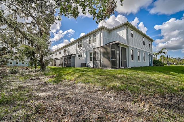 rear view of property with central AC, a lawn, and a sunroom