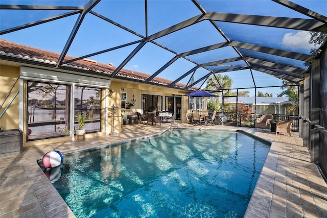 view of pool with glass enclosure, an outdoor hangout area, and a patio area