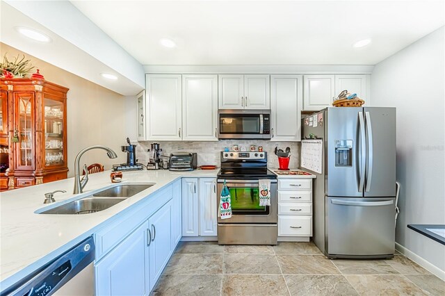 kitchen with white cabinets, sink, decorative backsplash, light stone countertops, and appliances with stainless steel finishes