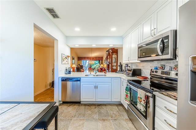 kitchen with white cabinets, appliances with stainless steel finishes, kitchen peninsula, and sink