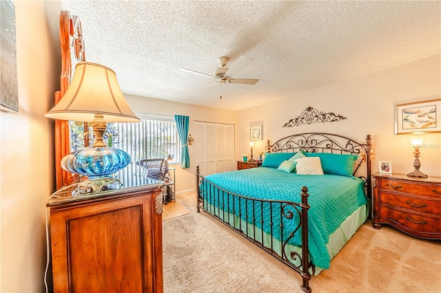 bedroom featuring ceiling fan, a closet, light colored carpet, and a textured ceiling