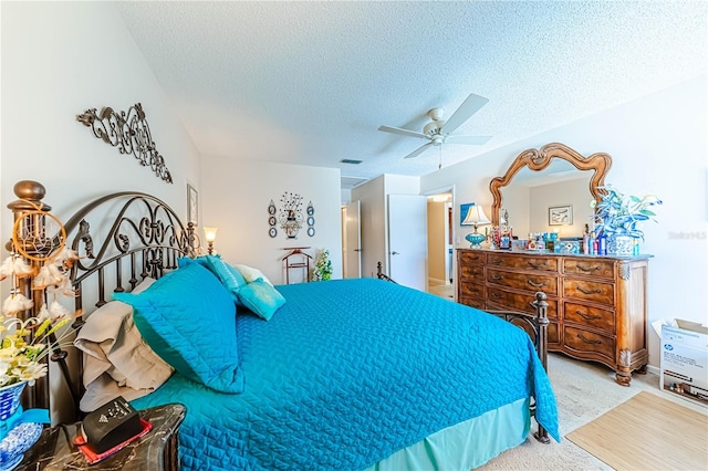 bedroom with ceiling fan, light colored carpet, and a textured ceiling