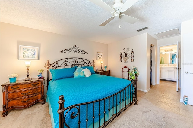 bedroom featuring ceiling fan, light colored carpet, ensuite bathroom, and a textured ceiling