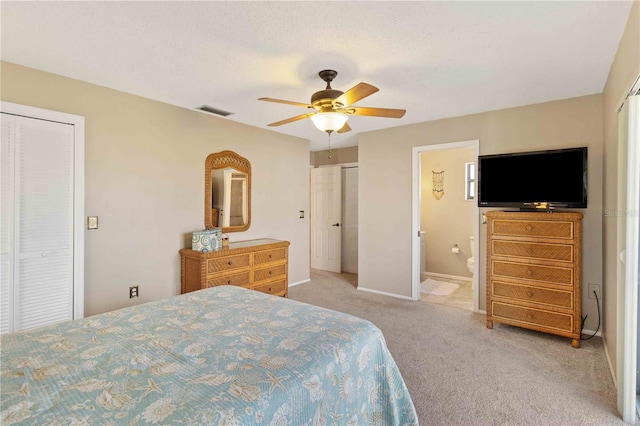 bedroom featuring ceiling fan, connected bathroom, light carpet, and two closets