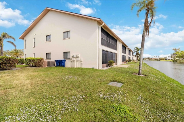 view of property exterior featuring central AC, a yard, and a water view