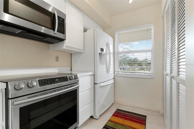 kitchen with white cabinets, appliances with stainless steel finishes, and light tile patterned flooring