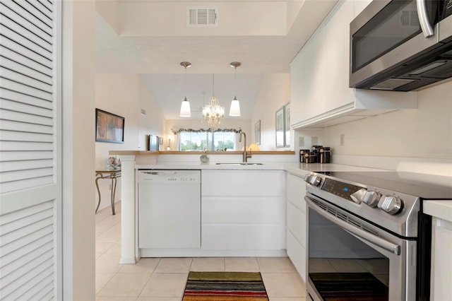 kitchen with kitchen peninsula, appliances with stainless steel finishes, sink, white cabinetry, and hanging light fixtures