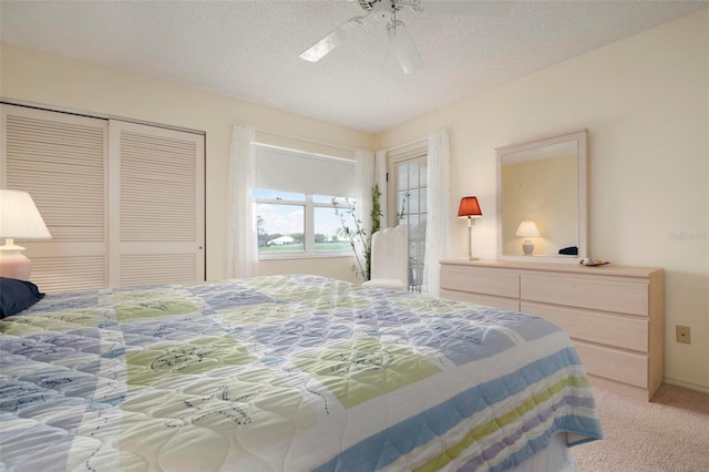 carpeted bedroom with ceiling fan, a textured ceiling, and a closet