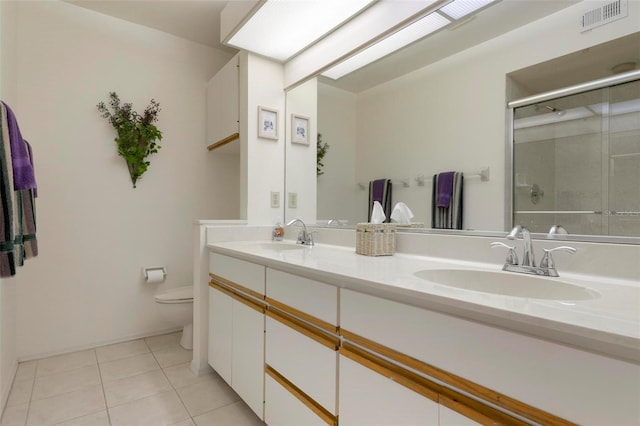 bathroom featuring tile patterned floors, vanity, a shower with shower door, and toilet