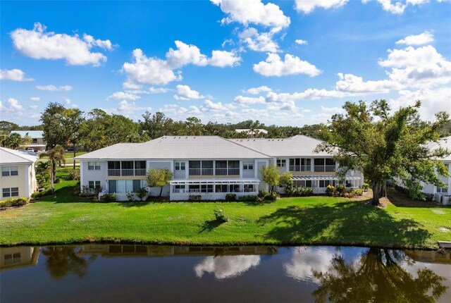 back of property with a yard and a water view