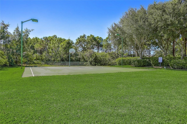 view of home's community featuring basketball hoop and a yard