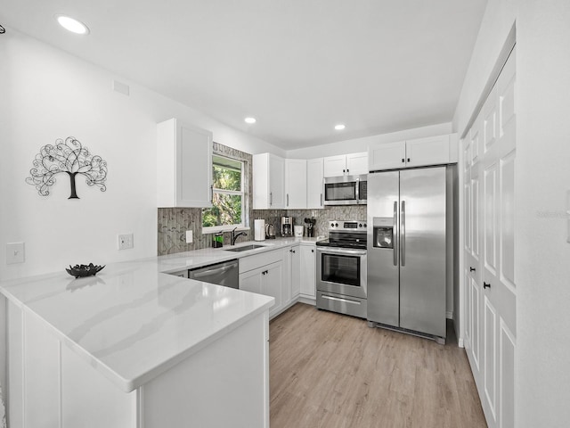 kitchen with white cabinetry, appliances with stainless steel finishes, sink, and kitchen peninsula