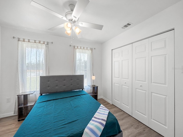 bedroom featuring a closet, light wood-type flooring, multiple windows, and ceiling fan