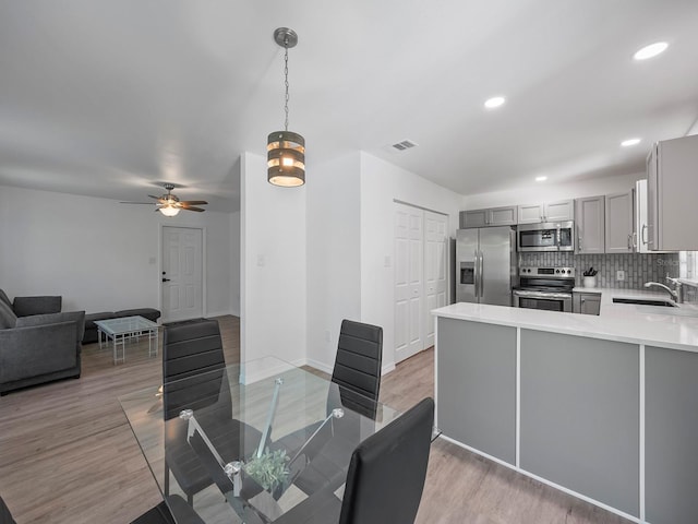 dining area featuring light wood-type flooring, sink, and ceiling fan