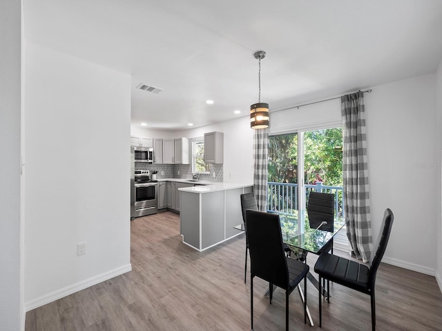 dining room with light wood-type flooring, sink, and a healthy amount of sunlight