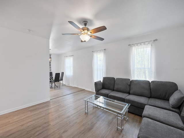 living room with a wealth of natural light, wood-type flooring, and ceiling fan