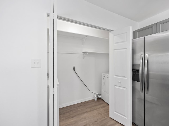 interior space with stainless steel fridge with ice dispenser, gray cabinetry, light wood-type flooring, and washer / clothes dryer