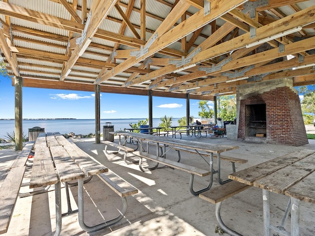 view of patio featuring a water view and an outdoor brick fireplace