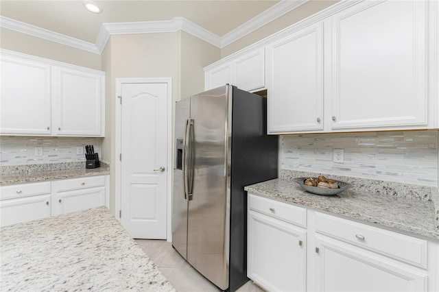 kitchen with white cabinets, ornamental molding, tasteful backsplash, light stone counters, and stainless steel fridge with ice dispenser