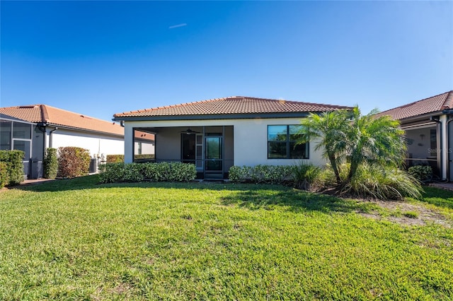 rear view of property featuring a yard, ceiling fan, and a sunroom