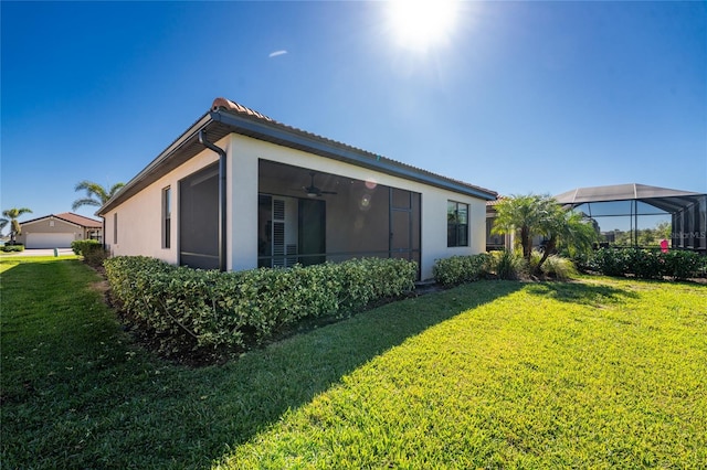 back of property featuring ceiling fan, a lanai, and a yard