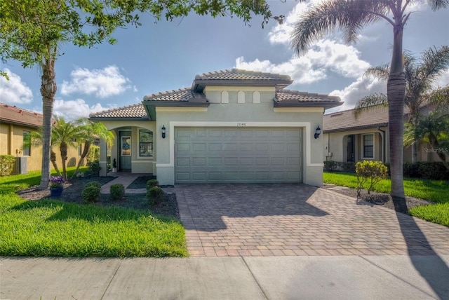 mediterranean / spanish home featuring a front yard and a garage