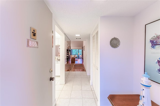 hallway with light tile patterned flooring and a textured ceiling